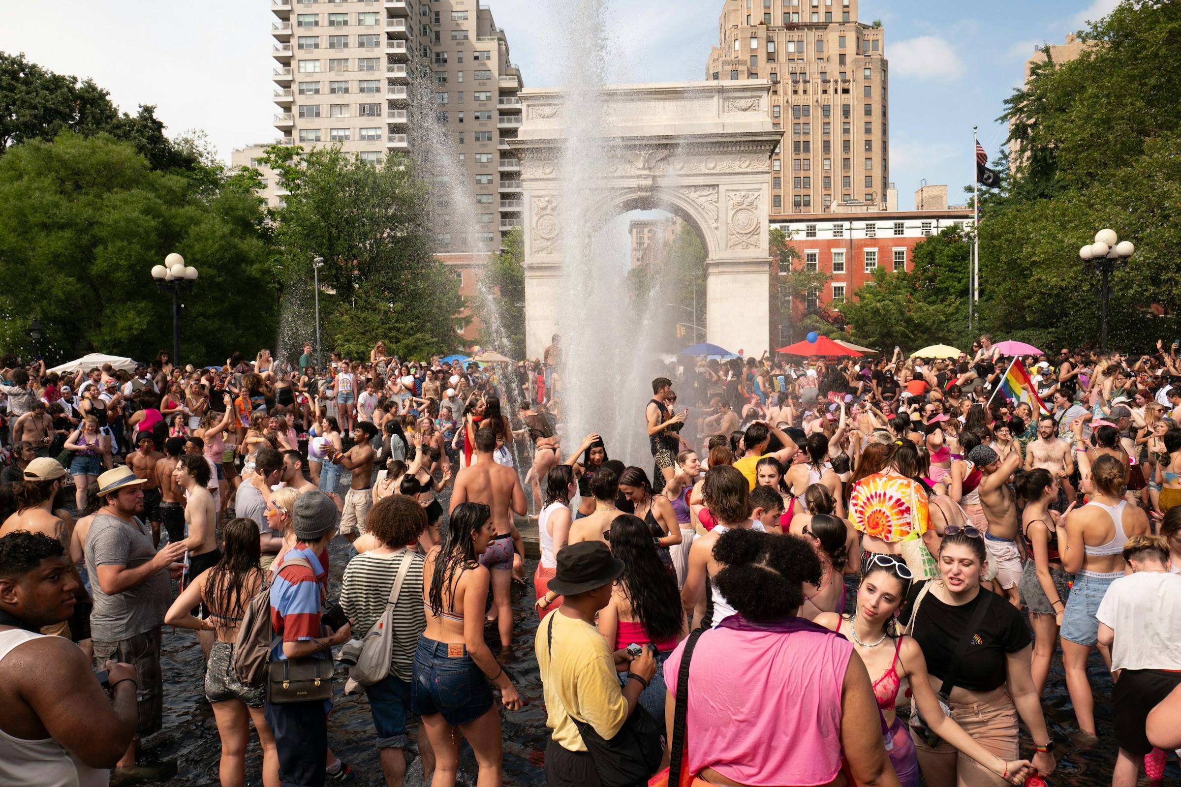 A packed, dancing crowd around the Washington Square Park fountain and arch during Pride 2023