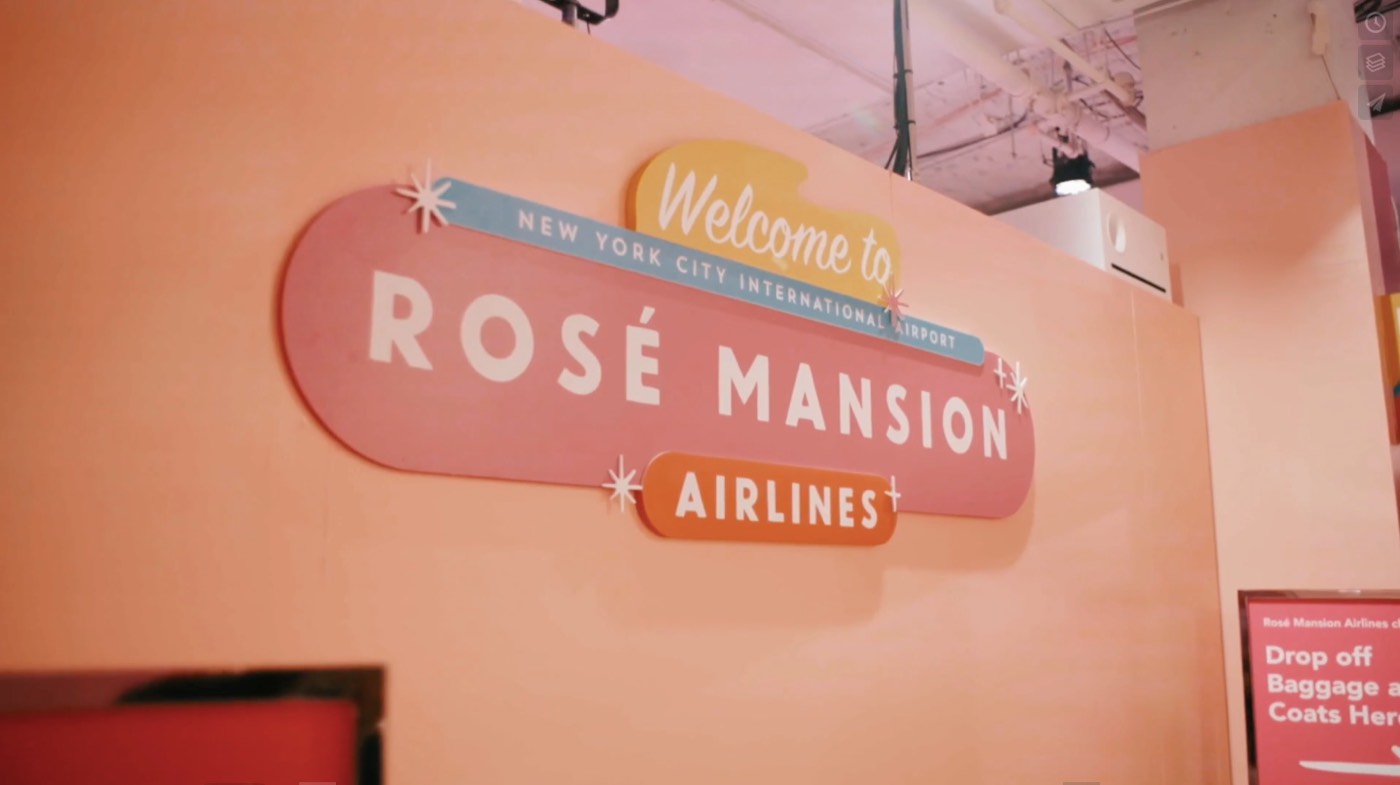 A pink Welcome to Rosé Mansion Airlines sign on a peach wall