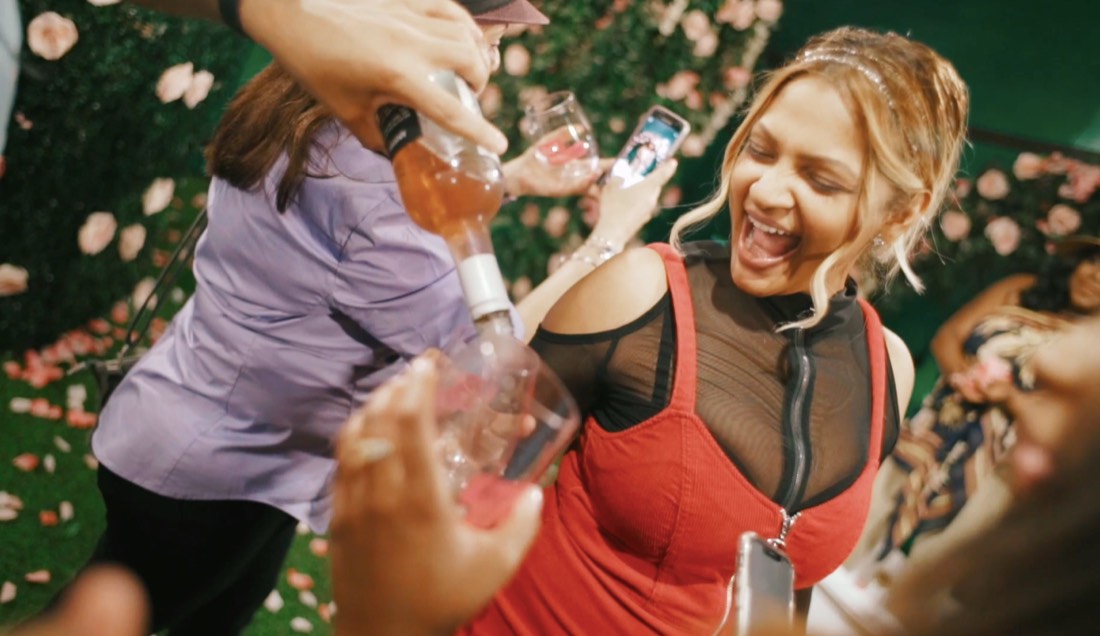 A guest laughing as rosé is poured for her in a room of pink flowers